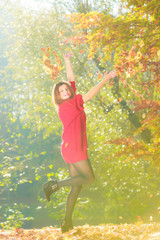 Young woman tossing leaves.