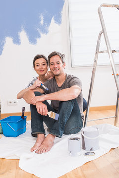 Handsome couple painting walls of their new home