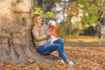 Young woman playing with her dog  in the park and smiling
