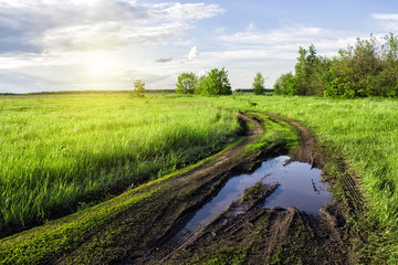 The mud and puddles after a rain on a country road in the field. Autumn landscape.
