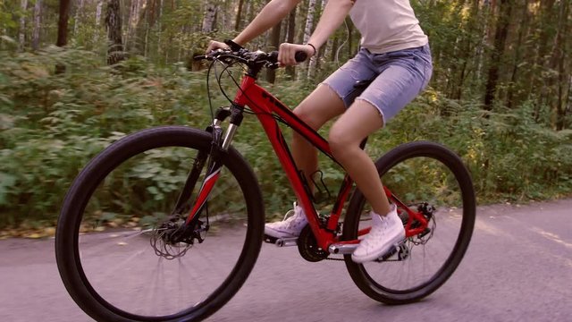 Close-up of blond girl riding her bicycle in the forest