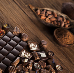 Chocolate bars and pralines on wooden background
