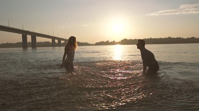 Young cheerful couple having fun in the water on a hot summer evening