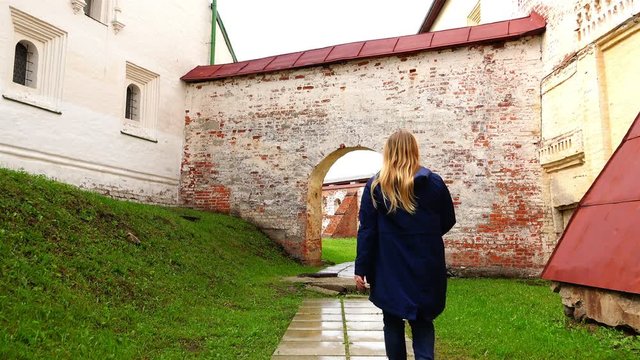 girl goes on a wet track at the old arched architectural arch connecting the two historical buildings