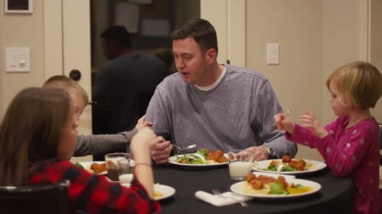 A family sitting down to have spaghetti and meatballs for dinner