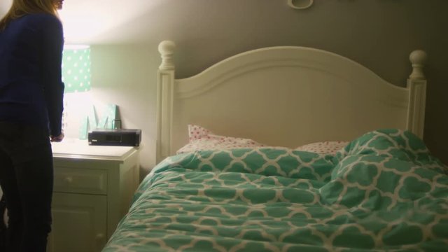A woman turning off the lights in her daughter's bedroom after she tucks her in