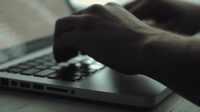 Man hands typing on a keyboard using his laptop computer