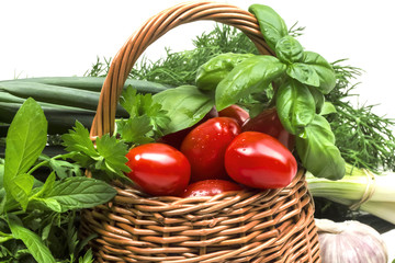 Fresh juicy fragrant herbs with a basket of small red tomatoes c