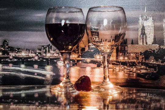 glass filled with wine next to an empty glass at dusk