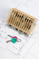 Home keys and small house under construction on electrical drawings, building home concept