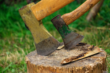 two ax in stump with wood crest on a background of green grass