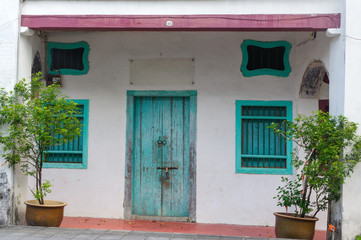 Fototapeta na wymiar House in George Town, Penang, Malaysia. Mediterranean style exterior. Blue wooden doors and window shutters on old painted wall