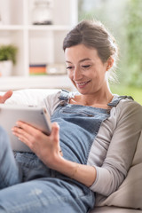Obraz premium young pregnant woman at home using a tablet