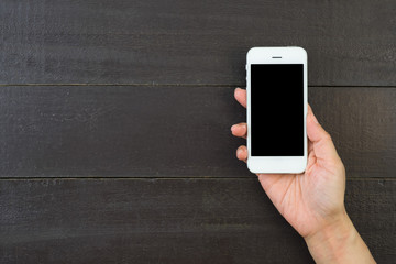 Woman hand holding and using mobile,cell phone,smart phone with isolated screen on wooden table or wooden floor for background.