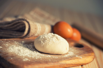 Fresh raw dough on a wooden cutting board