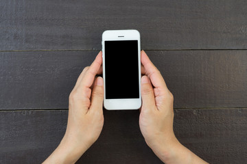 Woman hand holding and using mobile,cell phone,smart phone with isolated screen on wooden table or wooden floor for background.
