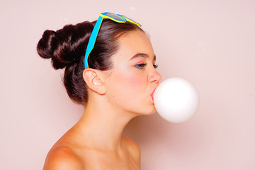 teenager girl blowing a bubble gum balloon