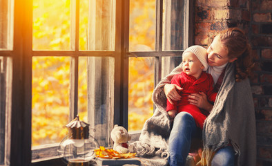 happy family mother and baby playing and laughing at window in f