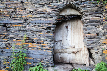 Broken door on stone wall