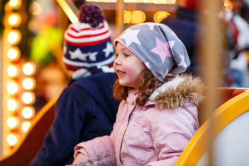 little boy and girl, siblings on carousel at Christmas market