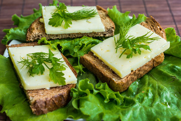 Three sandwiches lying on a plate. The greens, cheese and bread stacked in a sandwich.
