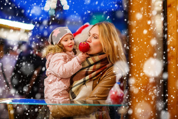 Woman and little girl eating crystalized apple on Christmas mark
