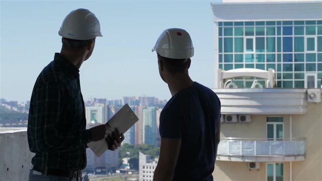 Builder points at the penthouse near the building under construction