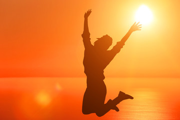 Successful woman jumping, dancing and having fun on sunset in beach. Freedom and happiness concept. Girl celebrating work out success.