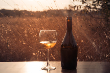 Bottle of white wine and a glass on a background of sunset savan