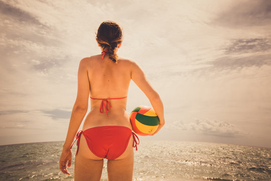 healthy young woman laughing with beachball while on the beach in summer