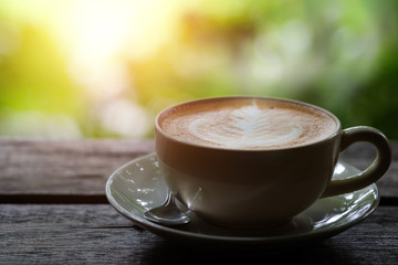 Hot coffee on a wooden table on green background