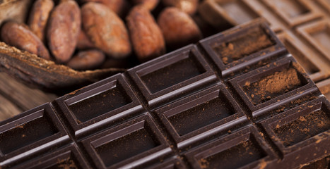 Dark homemade chocolate bars and cocoa pod on wooden