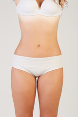 A woman is testing the skin on the thigh for the presence of stretch marks and cellulite