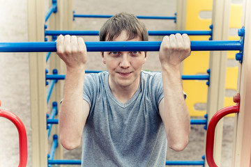 Naklejka premium Man doing physical exercises - pulling. Hanging on the bar. 