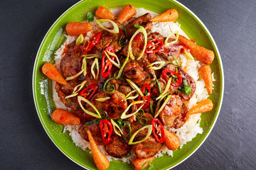 takeawy classic pork on rice with fried in sticky souce carrots, sprinkle of chillie and spring onion.