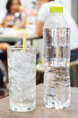 plastic bottle and ice glass on the table in restaurant background
