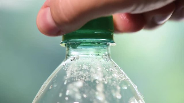 Hands opening a bottle of fresh mineral water - in slow motion fullHD video. Close-up of plastic bottle cool soda water. 
