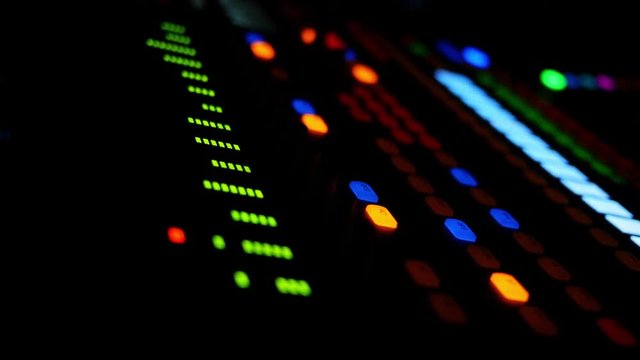 A close up view of an electronic mixing board in a dark room.