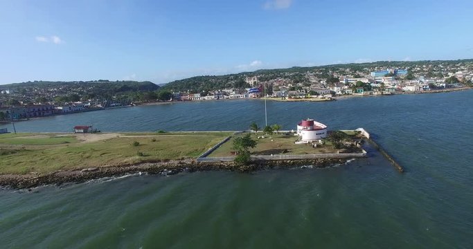Bird's-eye view from drone to landscape of small peninsula, big building on the caribbean shore and fluttering down wind Cuban flag nerby.