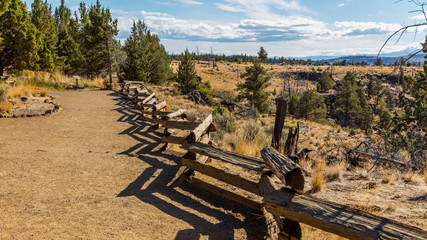 Wooden fence along the track. Huge mountains on horizon. Smith Rock state park, Oregon