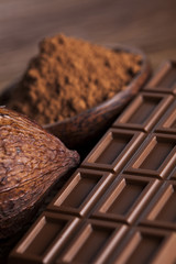 Chocolate bar, candy sweet, cacao beans and powder on wooden bac