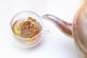 Herbal tea pouring from teapot to glass cup