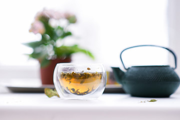 Teapot and glass cup with flower and herbal green tea