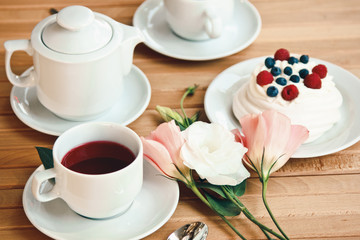 Fototapeta na wymiar Traditional dessert Pavlova cake with fresh berries and tea