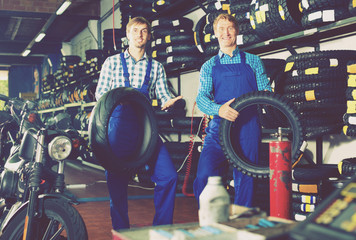 Two male professionals standing with new tires