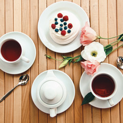 Traditional dessert Pavlova cake with fresh berries and tea