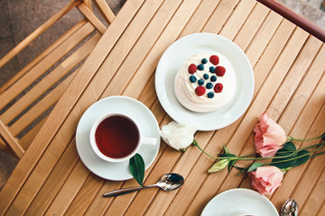 Traditional dessert Pavlova cake with fresh berries and tea