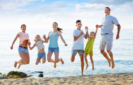 Large Family Jumping Up Together On Beach On Clear Summer Day