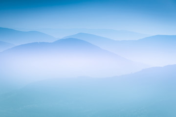 Landscape with colorful layers of mountains and haze in the valleys. The effect of color tinting.