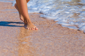 closeup woman legs on a sea beach